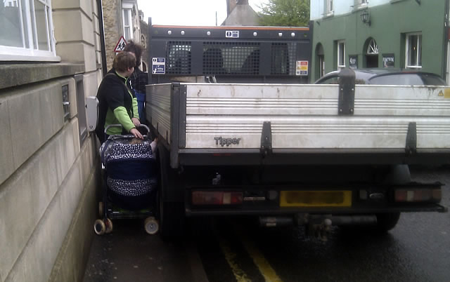 Mothers squeeze their prams between a bank and a truck