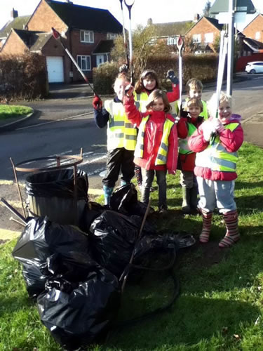 Local children with litter-picking equipment, and several filled bags