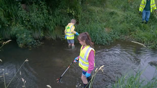 Kids in the river with litter-pickers