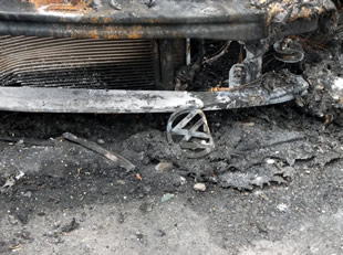 A burnt VW badge lying in the embers