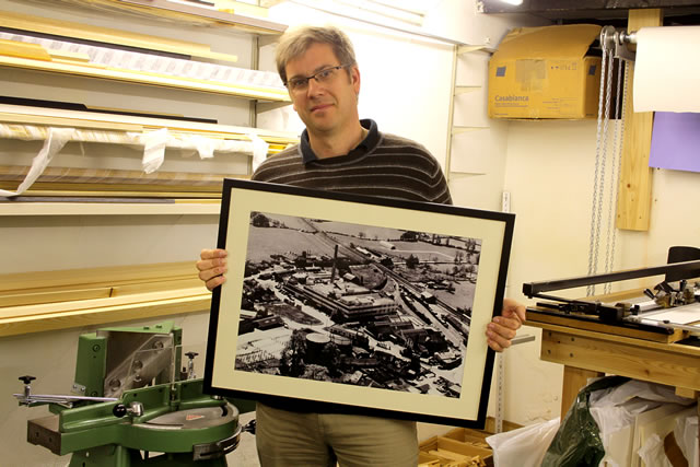 Graham in his framing studio with a restored print of the cow and gate factory