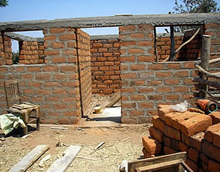 A small chicken house is being constructed from locally fired bricks
