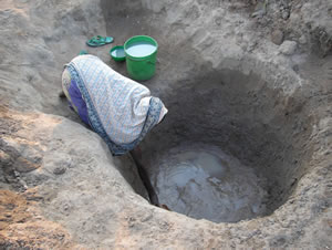 A villager collecting from a water hole
