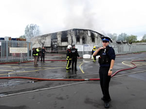 Firefighters at the scene, while a photogenic Police Officer strikes a convincing pose.