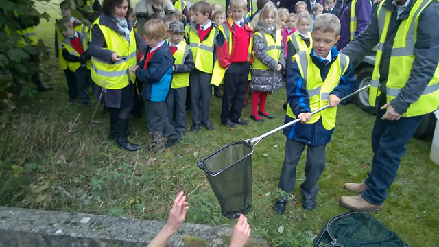 Children pass Jim nets of fish to release into the river