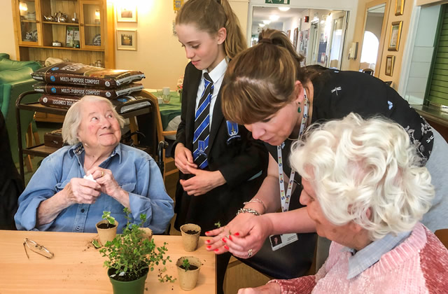 A King Arthur's student potting plants with a resident of Carrington House, Wincanton