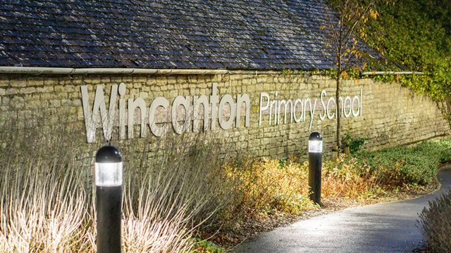 Wincanton Primary School entrance sign lettering, in the evening with the walkway lights on