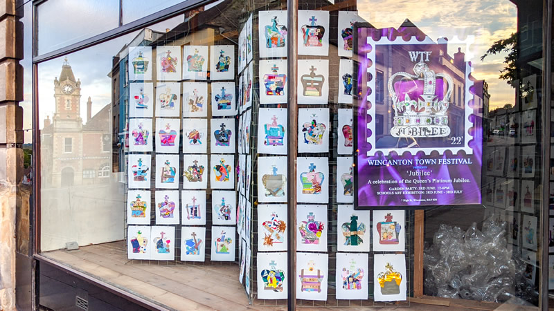 The Greening the eARTh gallery window, exhibiting the WTF 'Jubilee' event poster, and many of the children's postage stamp crown artworks